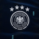 Camisa da Alemanha Away 2026 2027 Azul Marinho versão jogador oficial Adidas. Vista frontal mostrando o escudo termoaplicado em alta definição e detalhes verde-menta; detalhe aproximado da tecnologia do tecido respirável; vista das costas com corte slim fit e acabamento premium na gola. Palavras-chave: camisa alemanha 2026, camisa de time manga longa, uniforme alemanha reserva
