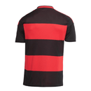 Frente da camisa oficial do Flamengo 2026-2027, listras horizontais pretas e vermelhas, escudo bordado e logo Adidas branco.