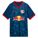 Vista frontal  da Camisa Away do Red Bull Bragantino 2025-2026, cor azul marinho. Apresenta um padrão geométrico radiante em azul cyan. A gola V e os punhos das mangas são vermelhos. Frente com escudo do clube, logos da Puma e patrocínio central Red Bull. Costa com "REDBULL BRAGANTINO", o nome "MASSA BRUTA" e o número "25" em branco.