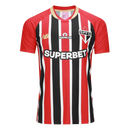 Camisa oficial reserva (Away) do São Paulo FC 2025/26, versão Torcedor, da New Balance. A peça exibe as icônicas listras verticais vermelhas, pretas e brancas com cores profundas e nítidas. Apresenta gola redonda preta com detalhes em dourado metálico, que também decoram as bordas das mangas. O escudo do clube é aplicado em patch bordado de alta definição no lado esquerdo, contrastando com o logo da marca em dourado à direita. O tecido possui uma trama respirável e toque macio, ideal para o uso casual de al