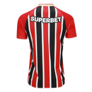 Camisa oficial reserva (Away) do São Paulo FC 2025/26, versão Torcedor, da New Balance. A peça exibe as icônicas listras verticais vermelhas, pretas e brancas com cores profundas e nítidas. Apresenta gola redonda preta com detalhes em dourado metálico, que também decoram as bordas das mangas. O escudo do clube é aplicado em patch bordado de alta definição no lado esquerdo, contrastando com o logo da marca em dourado à direita. O tecido possui uma trama respirável e toque macio, ideal para o uso casual de al