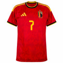 Camisa oficial da Seleção da Bélgica 2026-27, modelo titular (Home) da Adidas na cor vermelha. A imagem destaca a visão frontal do uniforme com a personalização do jogador De Bruyne e o número 7 em amarelo. O tecido apresenta um padrão de chamas sublimadas por toda a extensão, com o escudo belga dourado e o logo da Adidas em destaque. Detalhes das três listras amarelas nos ombros e acabamento em preto na gola e mangas, perfeita para torcedores que buscam a nova camisa da Bélgica 2026 na Blanc Sports.