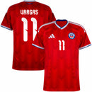 Visão Geral e Detalhes: Foto frontal da Camisa da Seleção do Chile Home 2026 vermelha, destacando o número 11 do atacante Eduardo Vargas. O texto alternativo descreve o padrão de tecido em zigue-zague, o escudo oficial da ANFP, as listras brancas nos ombros e a gola azul e branca. Inclui a visão das costas com a personalização "Vargas 11" e detalhes do tecido tecnológico, utilizando os termos: "Camisa Chile Vargas 11", "Nova Camisa do Chile 2026" e "Uniforme Chile Adidas Vermelho".