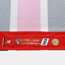Camisa oficial de jogo (versão Jogador) do São Paulo FC 2025/26 New Balance. A peça exibe as tradicionais listras verticais em vermelho e preto, separadas por finas linhas brancas, com cores vibrantes e acabamento fosco. O escudo do clube e o logo da marca são aplicados em relevo emborrachado (heat-transfer) para maior leveza. A modelagem é visivelmente ajustada (slim fit), com gola em "V" adornada por detalhes dourados sutis, transmitindo uma estética de alta performance e sofisticação técnica.